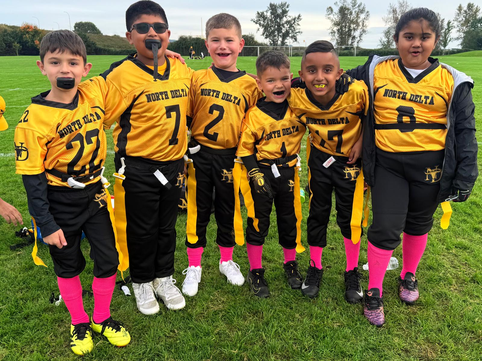North Delta Longhorns flag-tykes smiling after a game — gold jerseys and pink socks